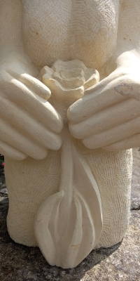 Detail of Natures protector garden sculpture in Maltese limestone with flower