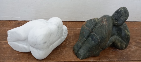 two stone carved reclining figures one dark green soapstone the other white carrera marble table top size